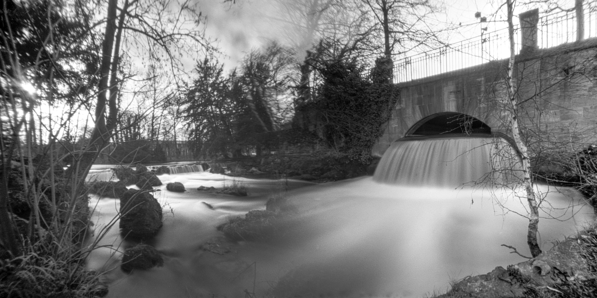 Lochkamera-Bild: eine Brücke über ruhiges Wasser, Schwarzweiß
