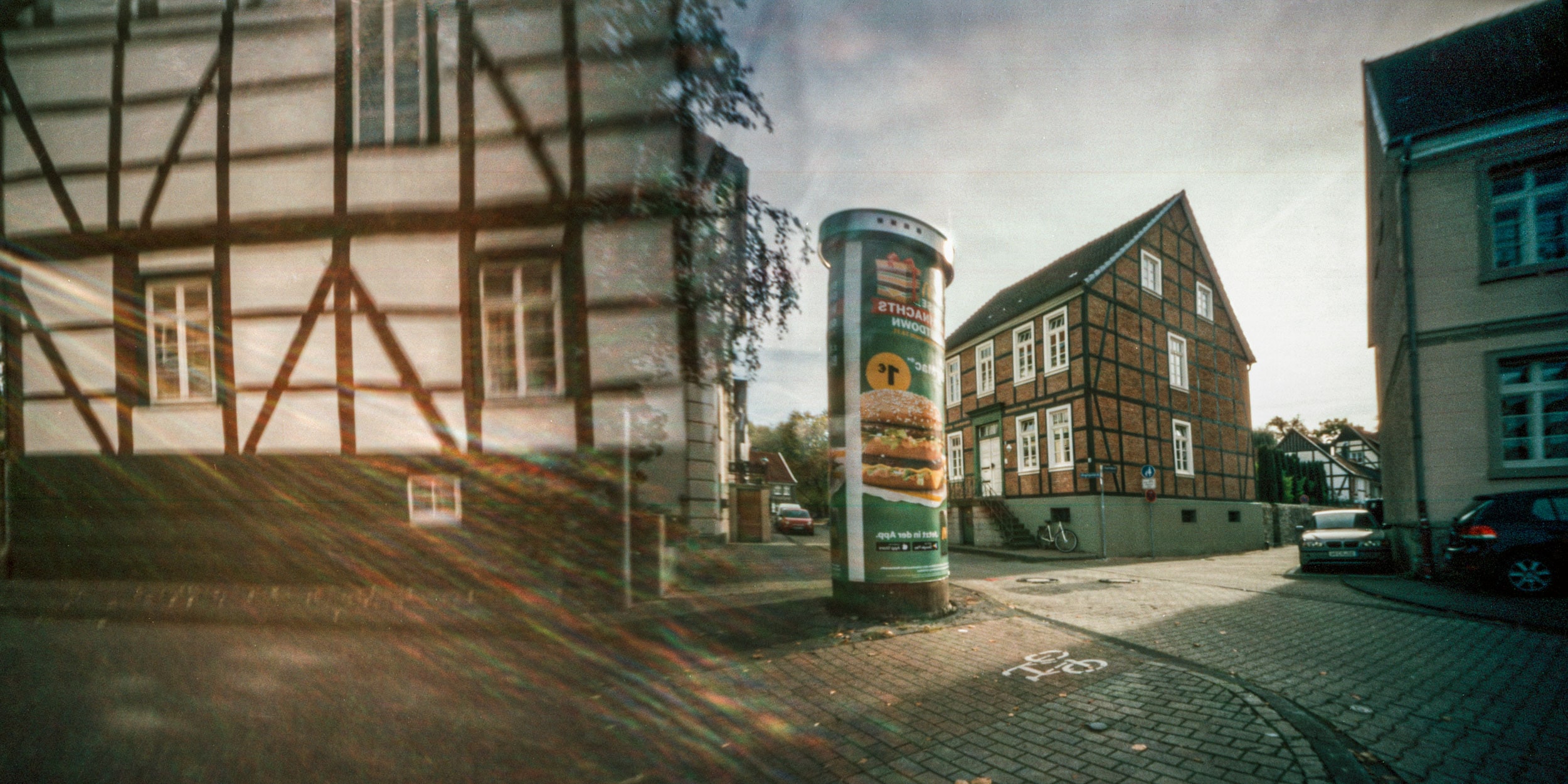 Lochkamera-Bild: eine Straßenecke mit Fachwerk und Litfaßsäule